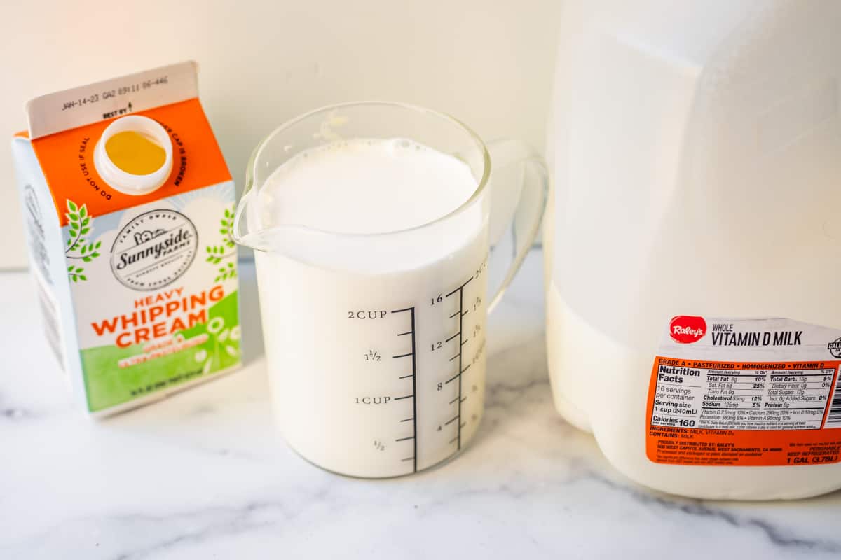 whipping cream container, glass cup of milk, and a gallon of milk.