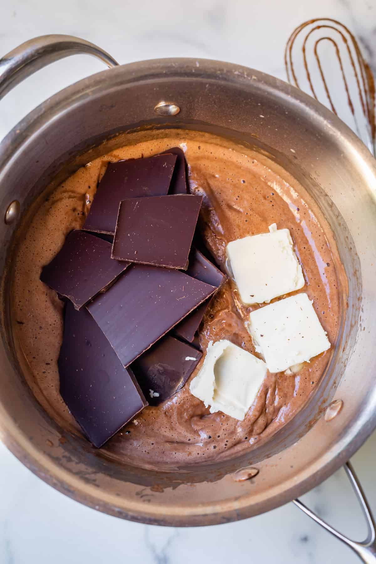 overhead shot of adding chocolate bar and butter to pudding in pot.