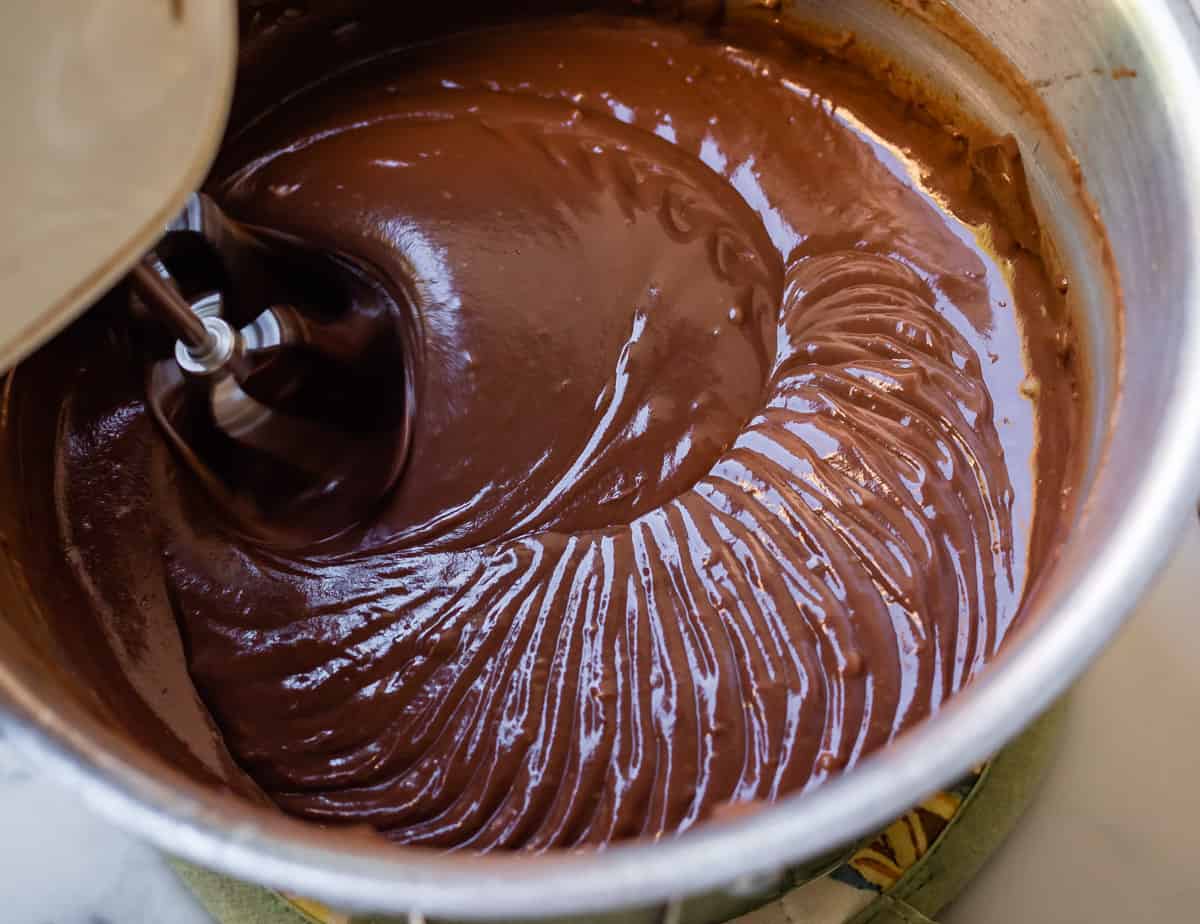 chocolate pudding in a pot being beaten with hand mixer.