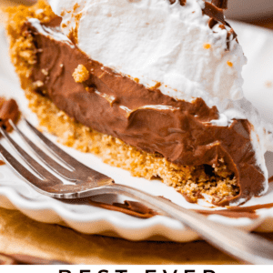 chocolate cream pie on a white plate with whipped cream and fork.