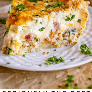 A slice of quiche with spinach and bacon sits on a white plate, topped with melted cheese and fresh herbs. The text below reads, Seriously delicious quiche with spinach & bacon. The Food Charlatan.
