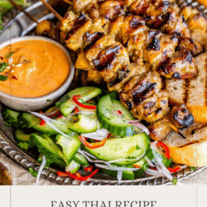 A plate of chicken satay skewers with peanut sauce, sliced cucumber salad, and lime wedges, with text reading “Chicken Satay – Get the Details!”.