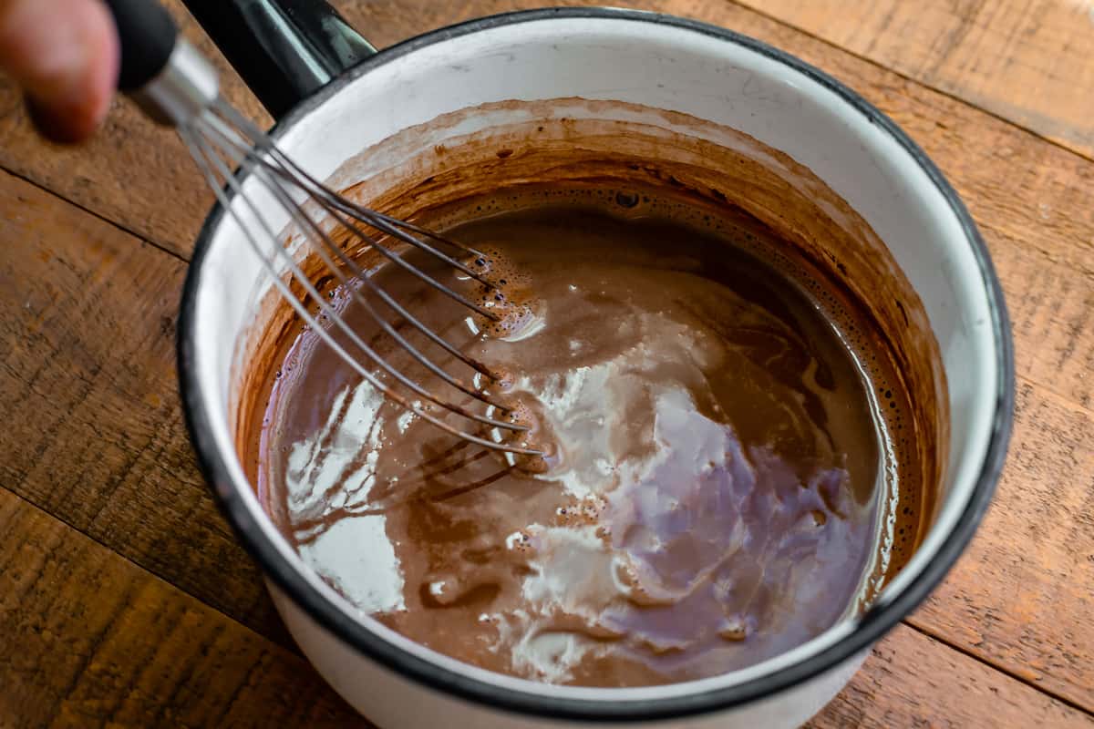 cocoa and water whisked in a white pot.