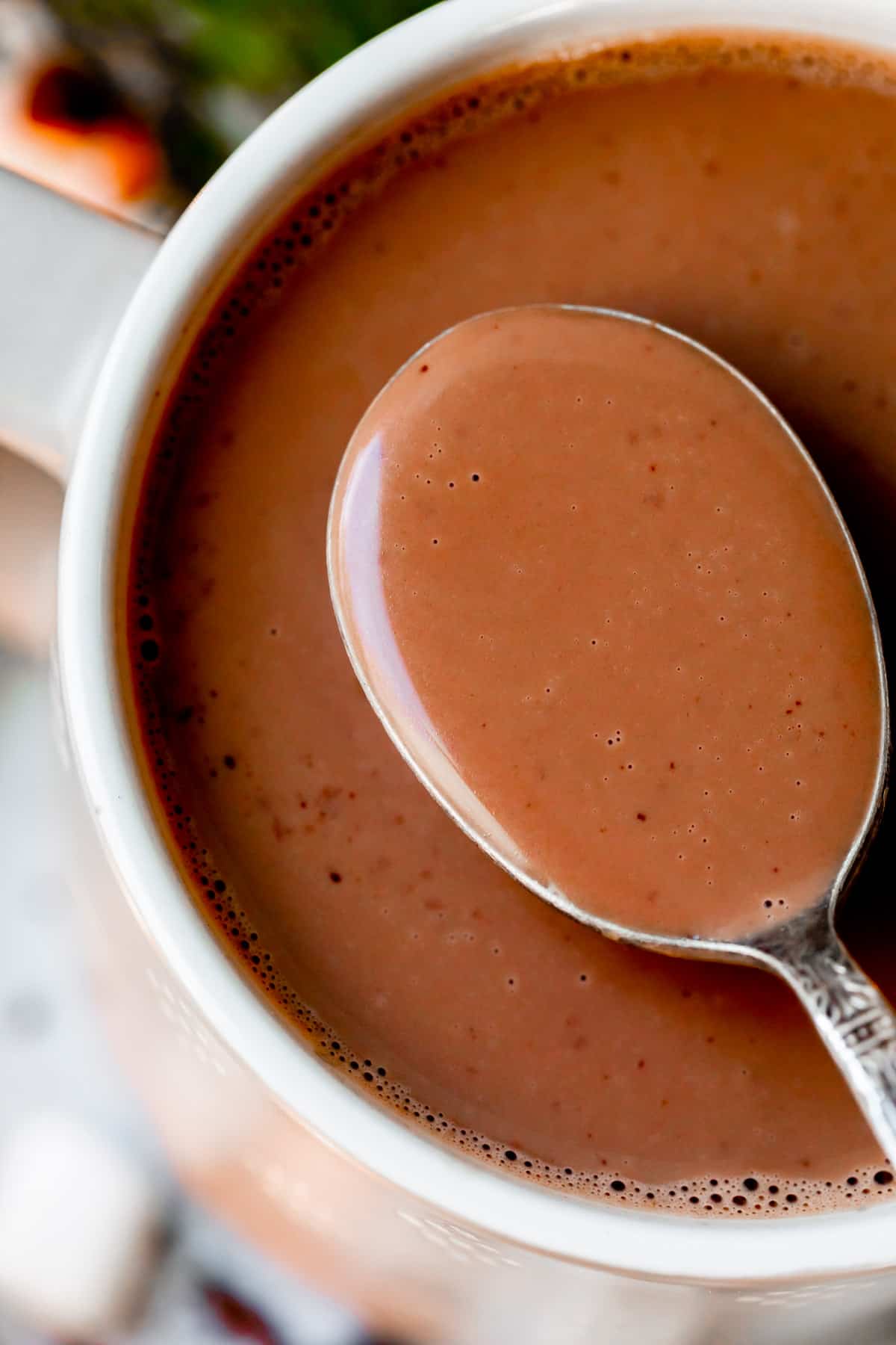 a spoonful of hot chocolate being lifted from a white mug.