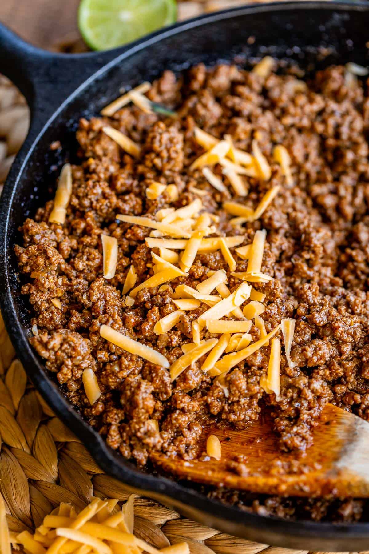 taco meat topped with shredded cheddar cheese in a cast iron skillet.