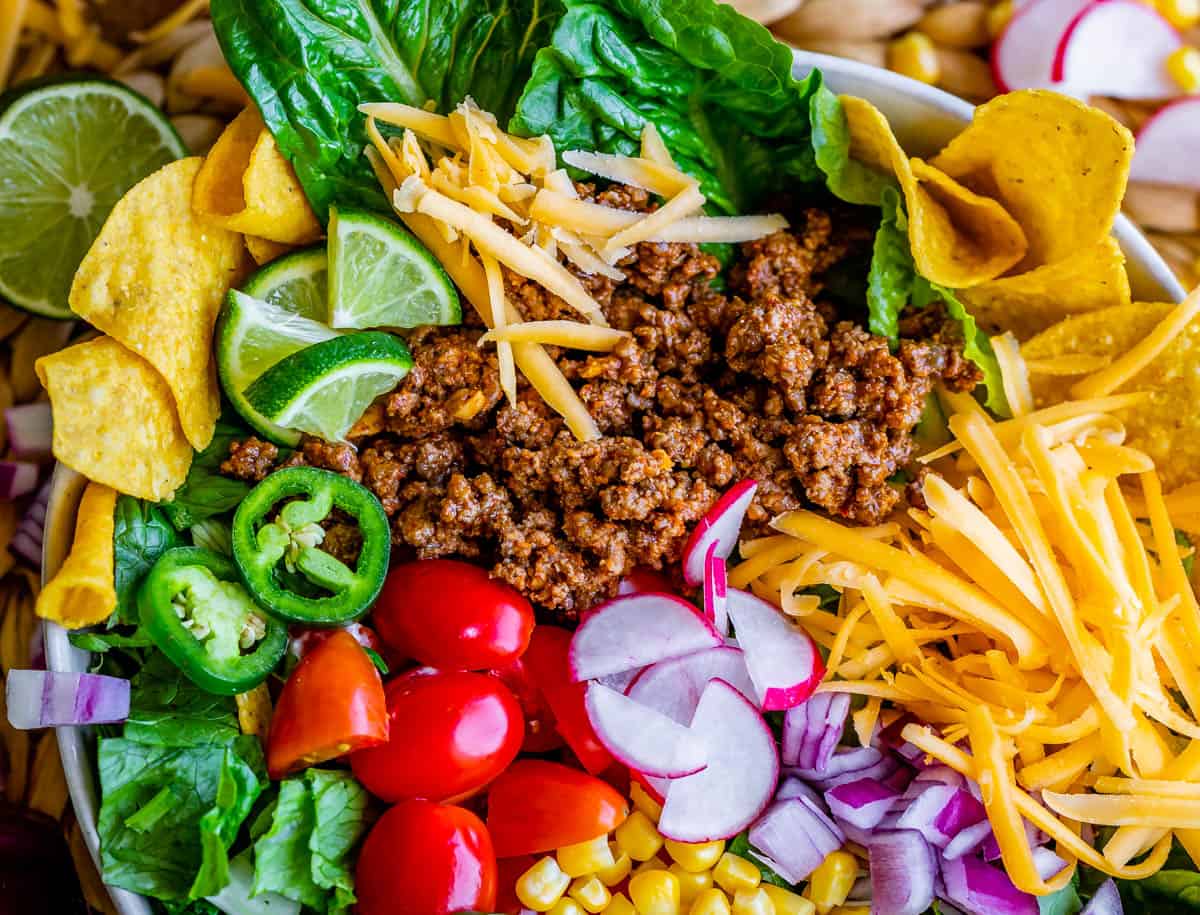 bowl of taco salad with radishes, lime, cheese, tomato, etc.