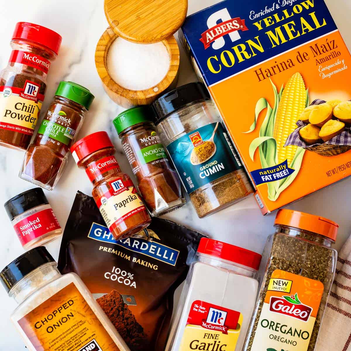 Mexican spices in containers and cornmeal spread out on a countertop.