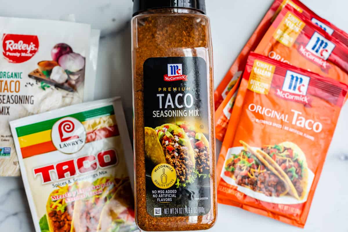several brands of pre made taco seasoning in their packaging, on counter.