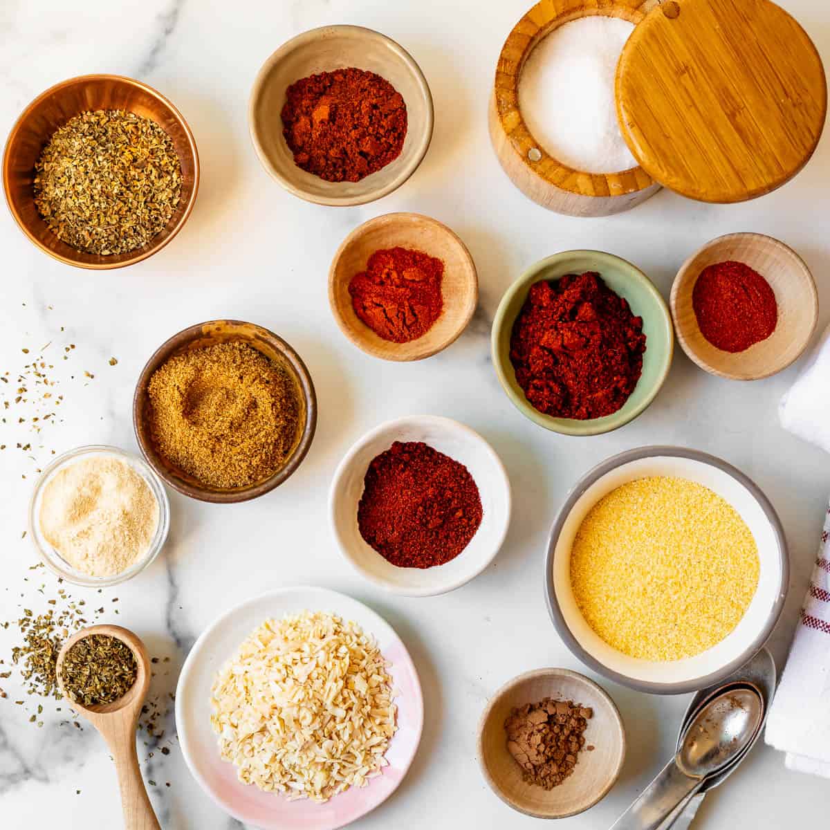 spices and ingredients for homemade taco seasoning in tiny bowls spread on a counter.