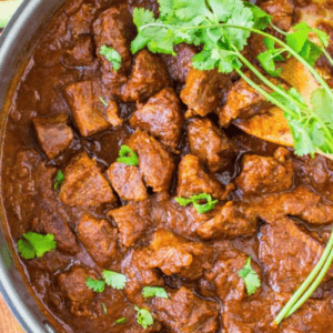 A bowl of carne guisada garnished with fresh cilantro.