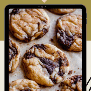 A tablet displays a close-up of cinnamon cookies with swirls of dark and light dough, set against a tan and olive green background. Text reads Cinnamon Roll Cookies and thefoodcharlatan.com.