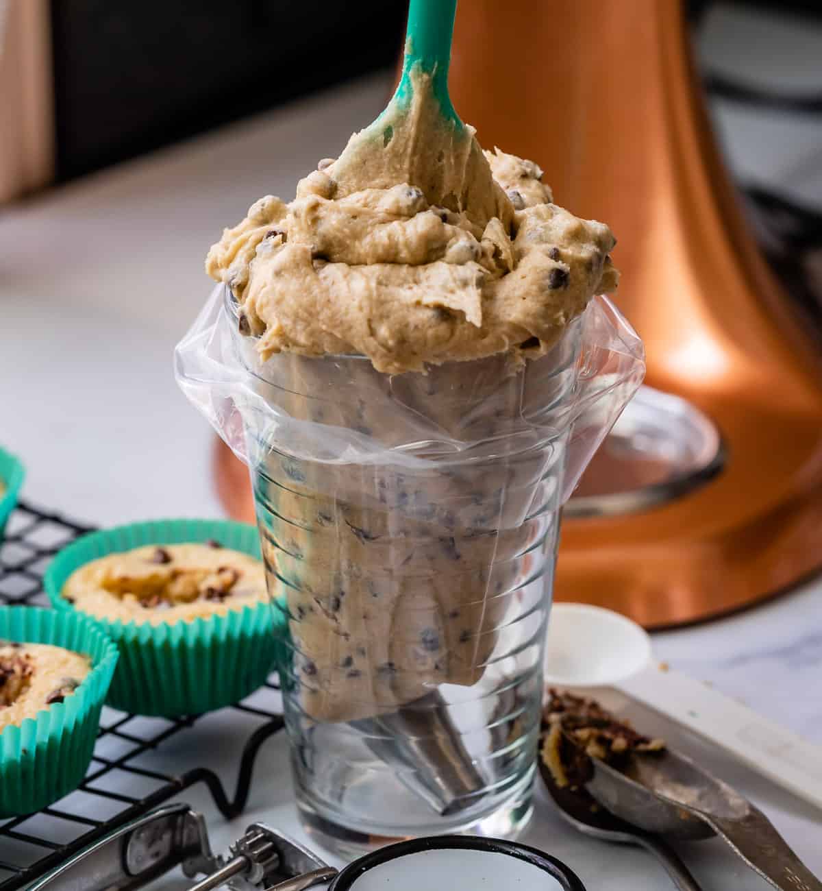 adding cookie dough frosting to an icing bag inside a glass.