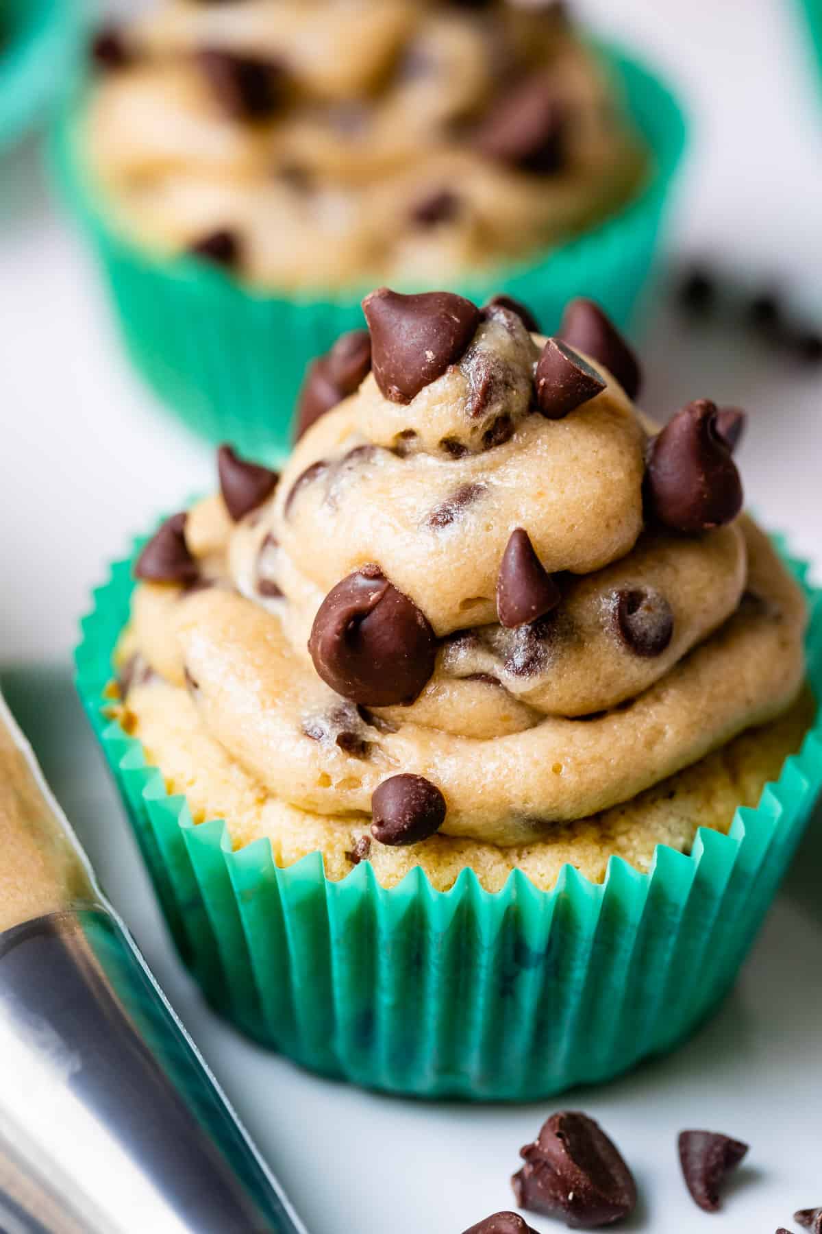 cupcakes in green liners with cookie dough frosting and mini chocolate chips.