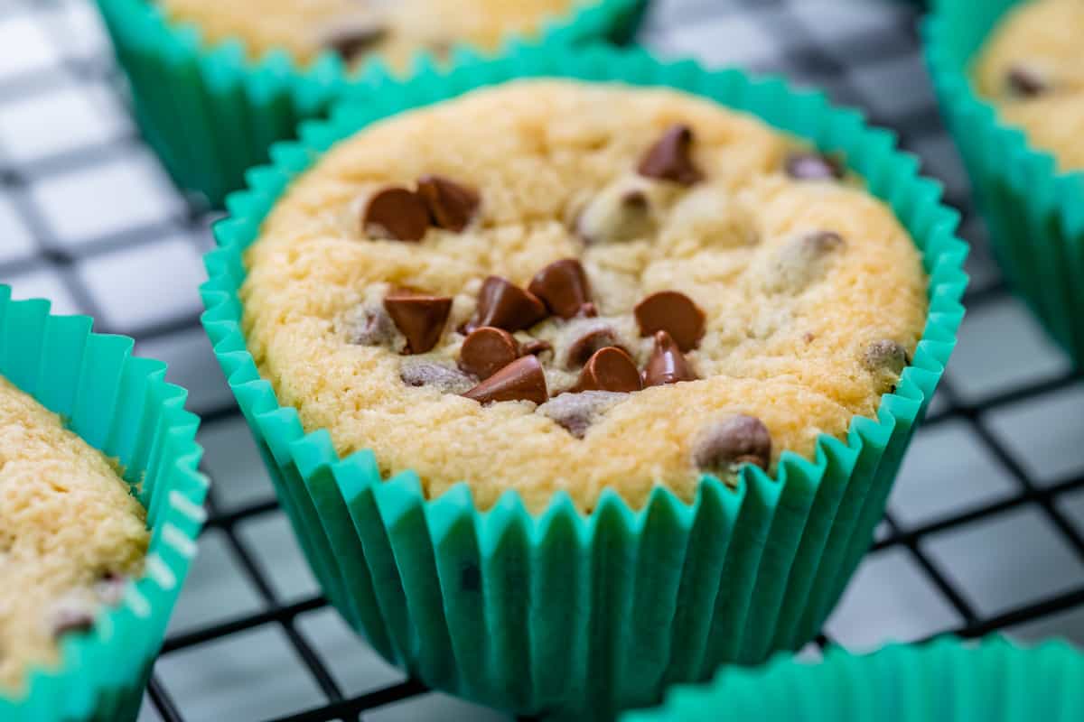 a cupcake with mini chocolate chips in a green cupcake liner on a cooling rack.