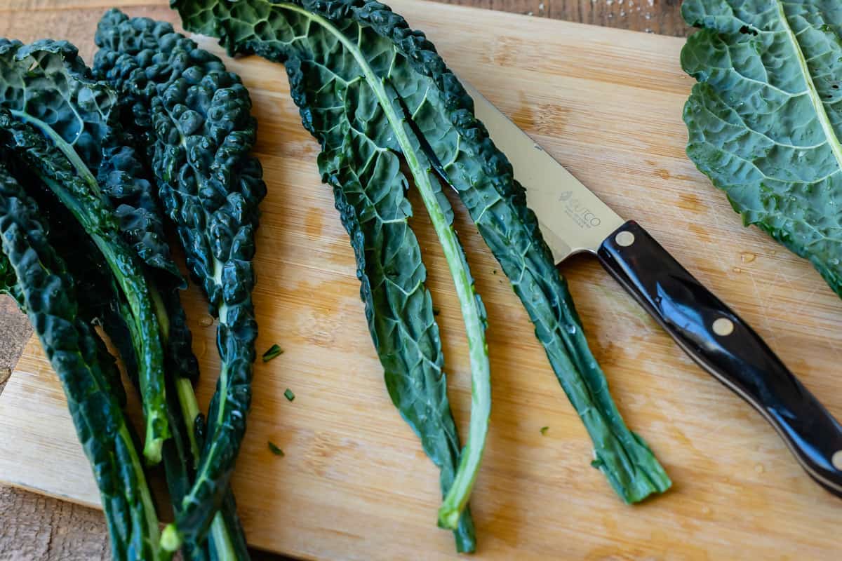 kale leaves on cutting board showing how to cut out the spine.