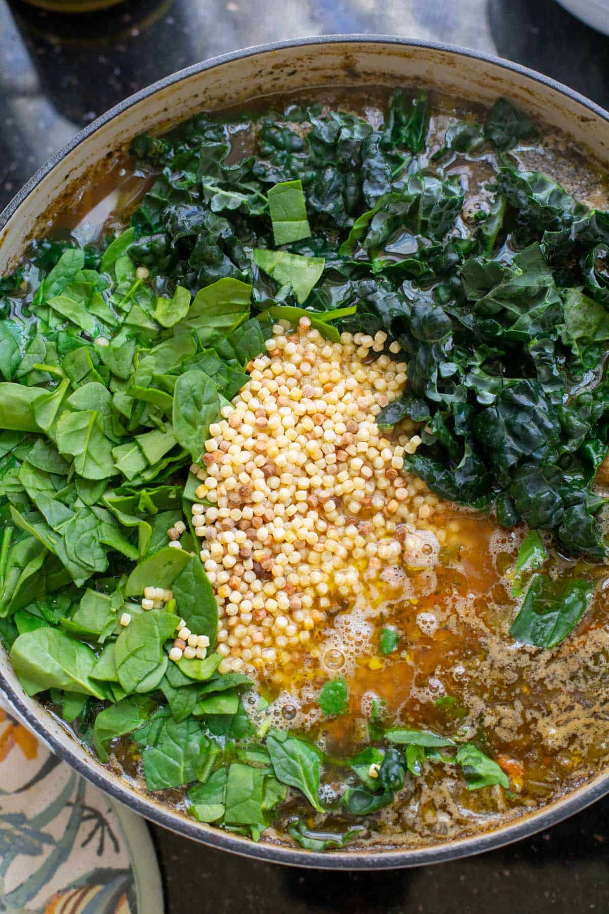 stock pot filled with broth, spinach, kale, and tiny pasta.