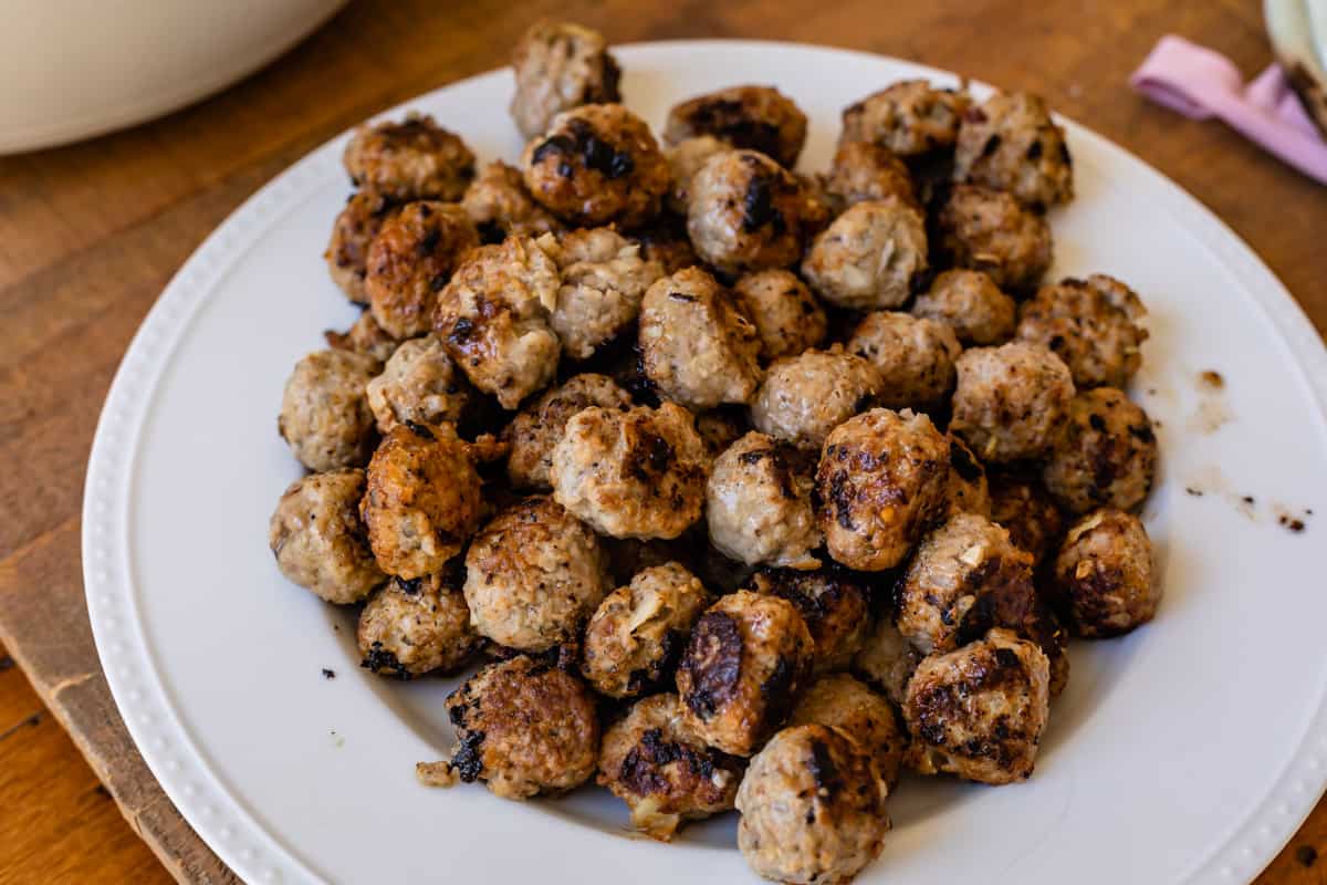 large pile of juicy browned meatballs on a white plate.