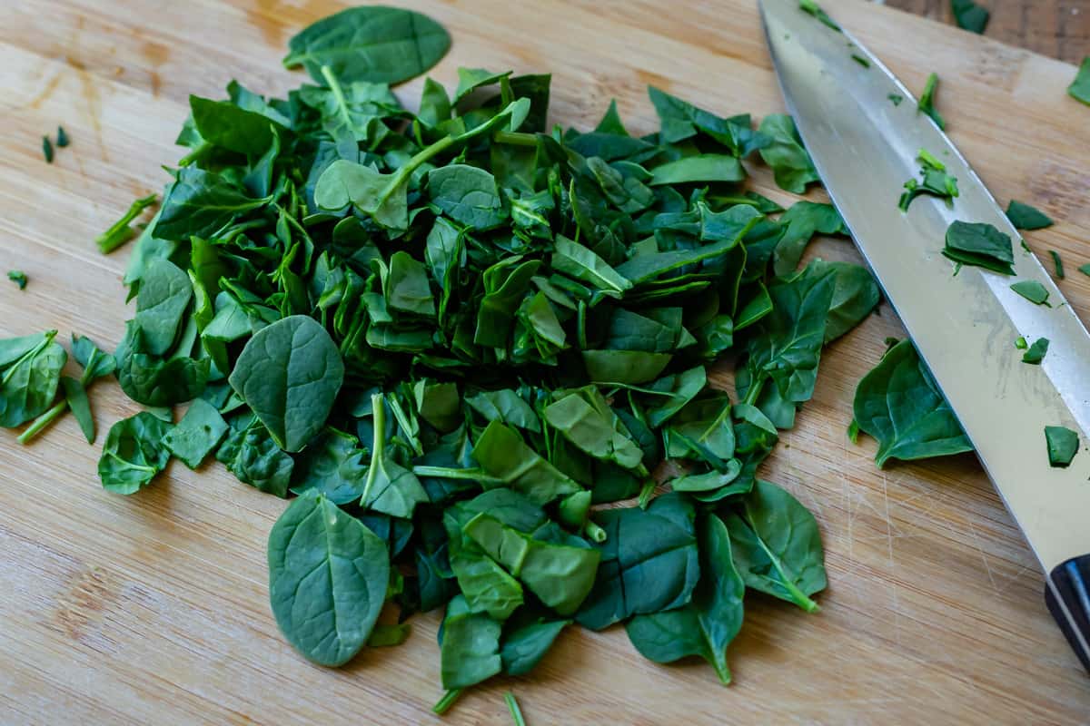 knife and chopped spinach on a cutting board to show chop size.
