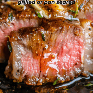 Close-up of a juicy, medium-rare ribeye steak with a seared, seasoned crust and a pink center, garnished with herbs. Text reads: Ribeye steak grilled or pan seared. Website: thefoodcharlatan.com.