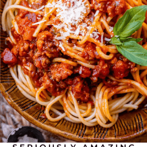 homemade spaghetti sauce with noodles in a bowl with parmesan and basil.