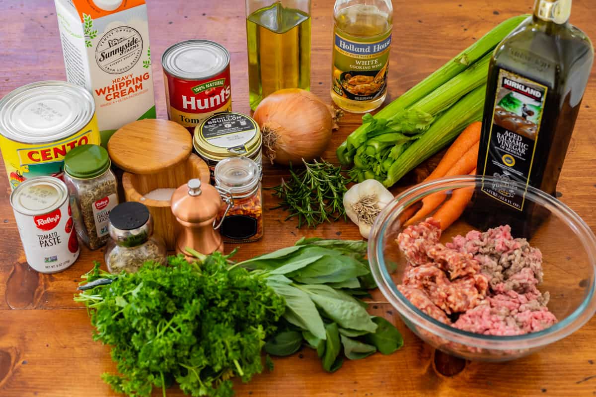 picture of ingredients lie onion, sausage, and tomatoes for homemade bolognese sauce.