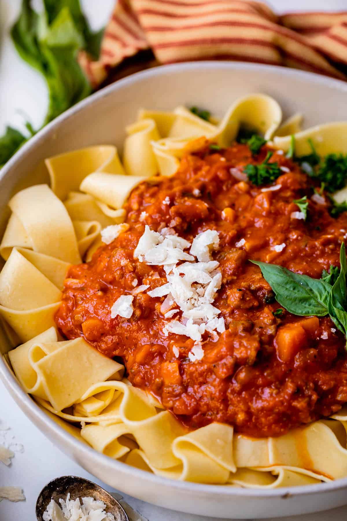 bowl of noodles with a healthy spoonful of red bolognese sauce served over the top.