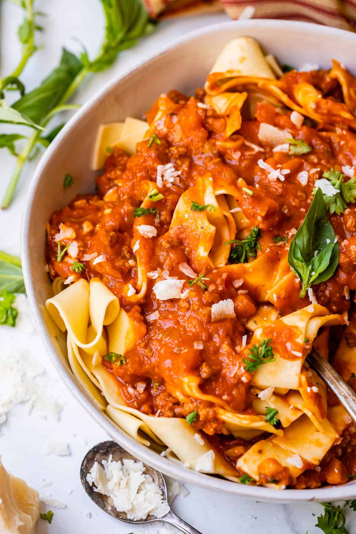 recipe for bolognese sauce on top of wide noodles, served in a bowl with a fork.