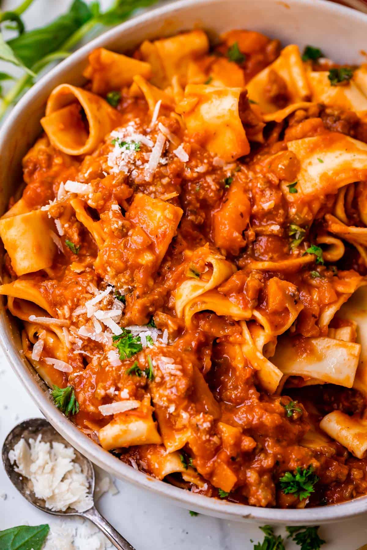 close up of bowl with meaty bolognese sauce topped noodles with parmesan garnish.