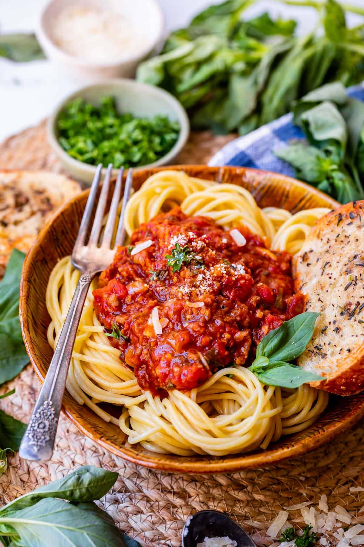 bowl of spaghetti noodles topped with easy sauce, with a fork and garlic bread on the side.