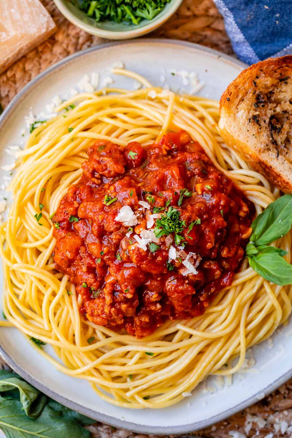 plate full of a artfully arranged spaghetti noodles with a neat scoop of red meat sauce on top.