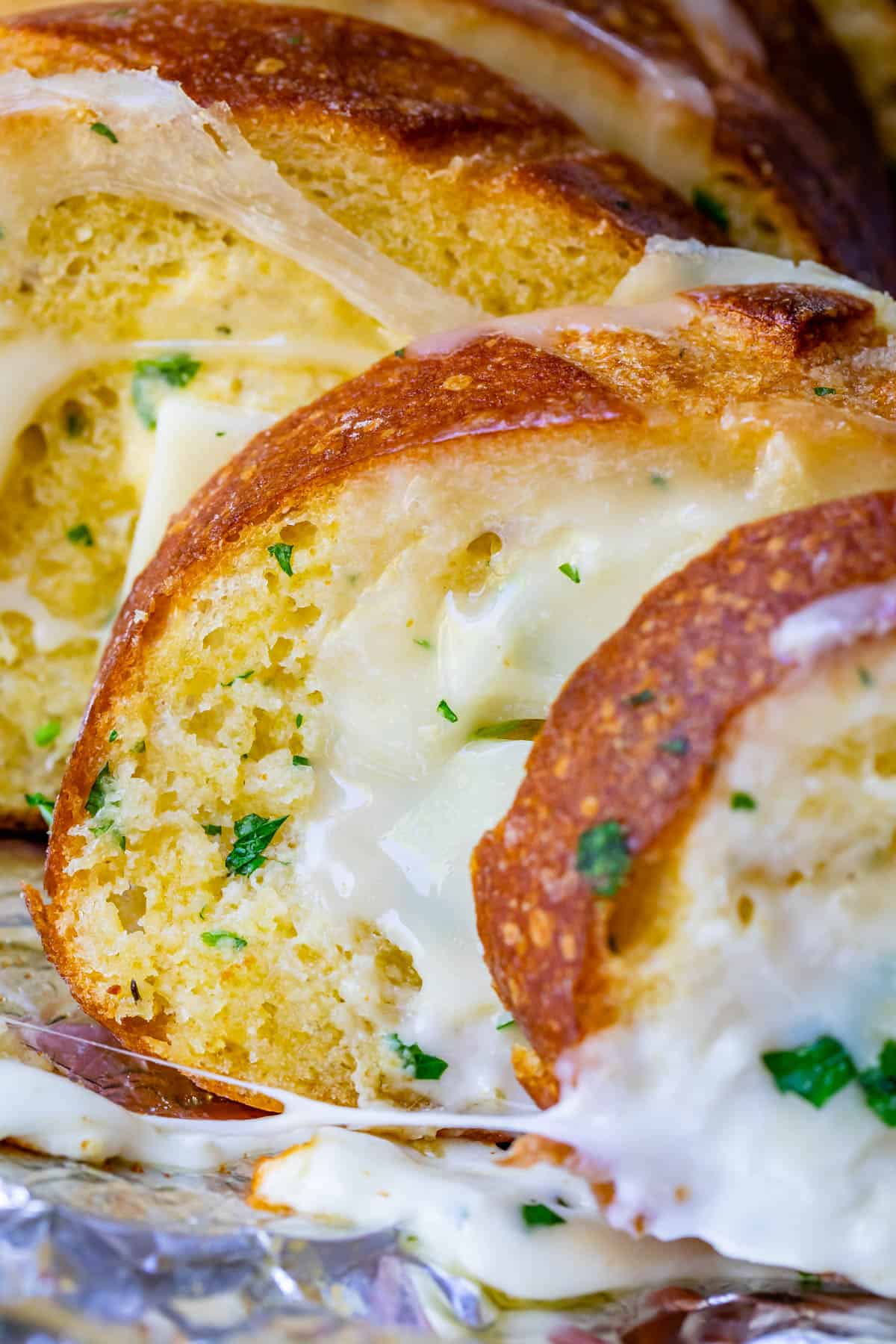 upright cheesy bread sprinkled with parsley on foil.