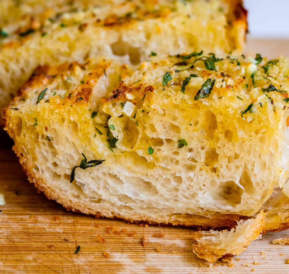 buttery homemade garlic bread with parsley and garlic on a cutting board.