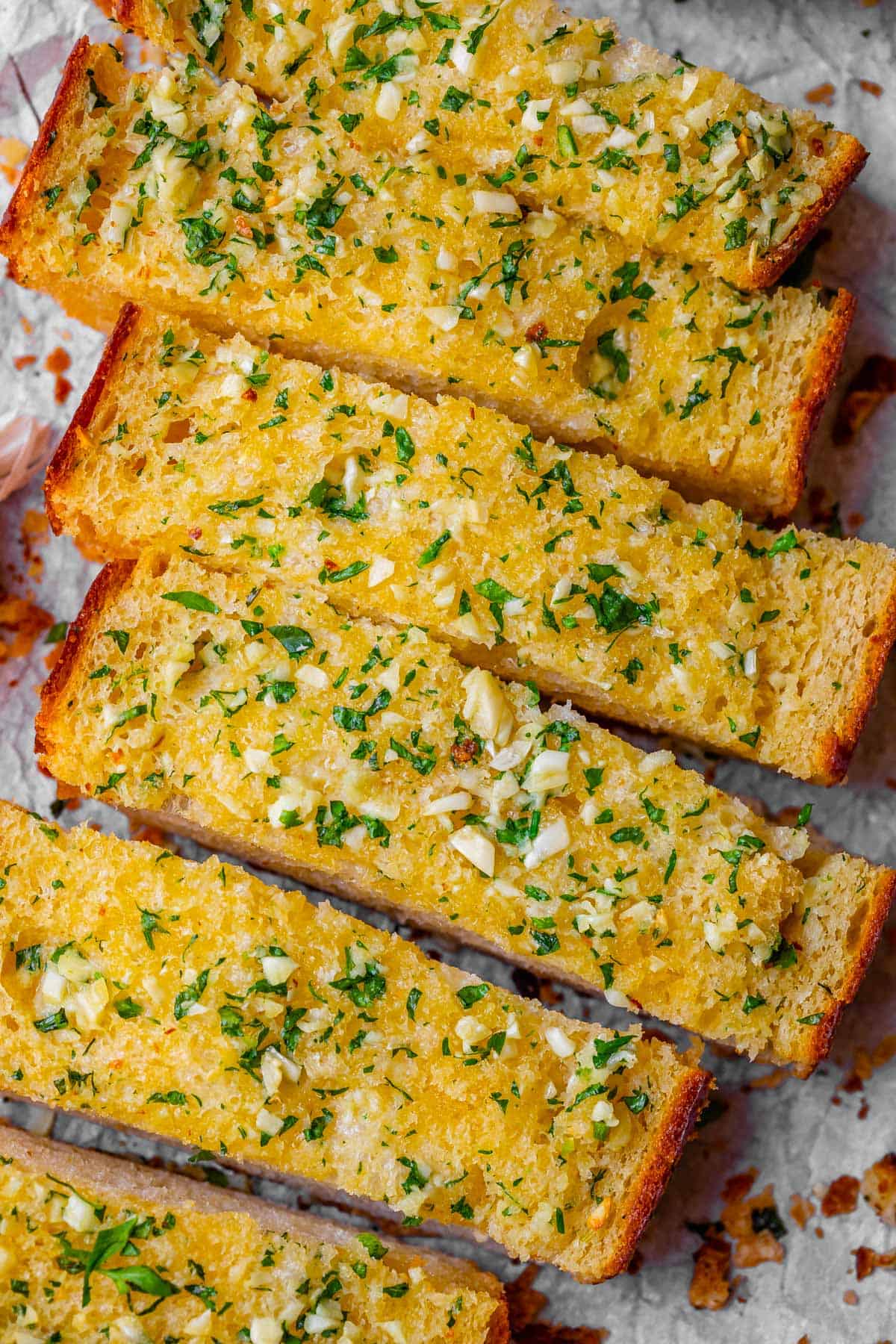 best garlic bread recipe, sliced and lined up on parchment paper.