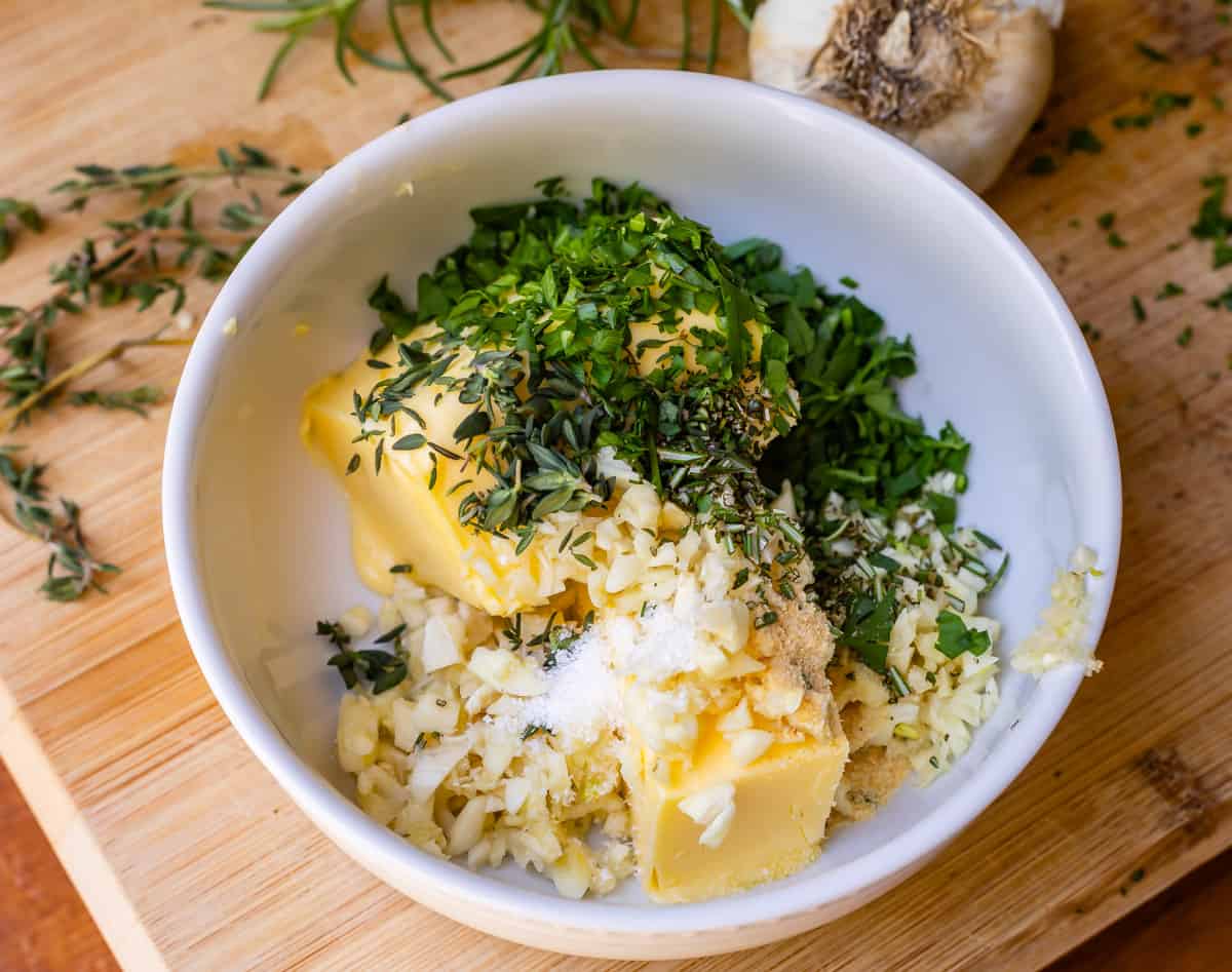 bowl with softened butter, garlic, parsley, and more to make butter for easy garlic bread.