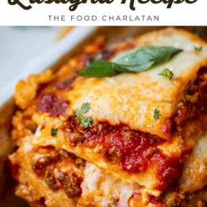 Close-up of a slice of homemade lasagna with melted cheese, tomato sauce, ground meat, and fresh basil on top. Text above reads Old Fashioned Lasagna - The Food Charlatan.