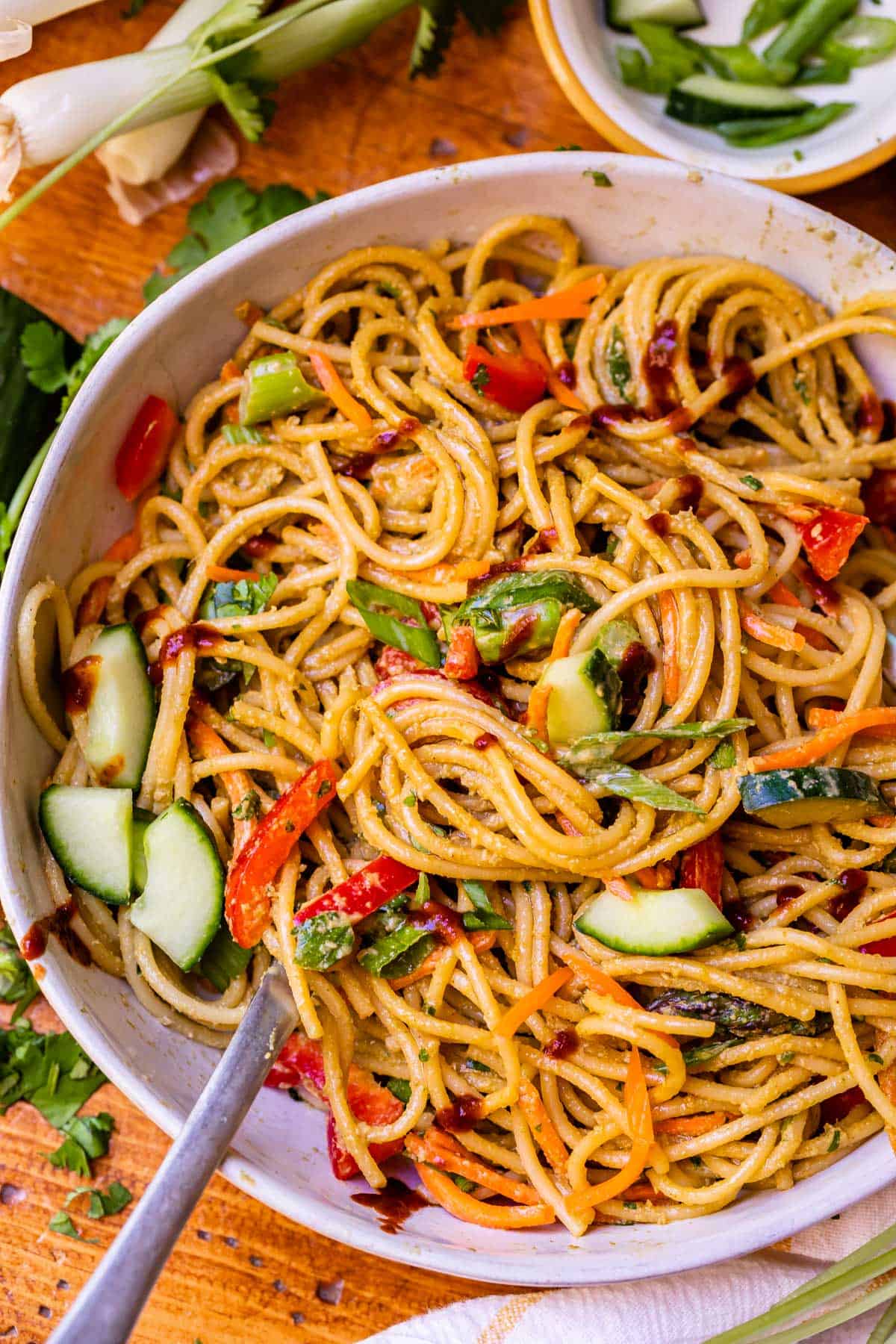 cold noodles with sesame sauce mixed with several vegetables in ceramic bowl.