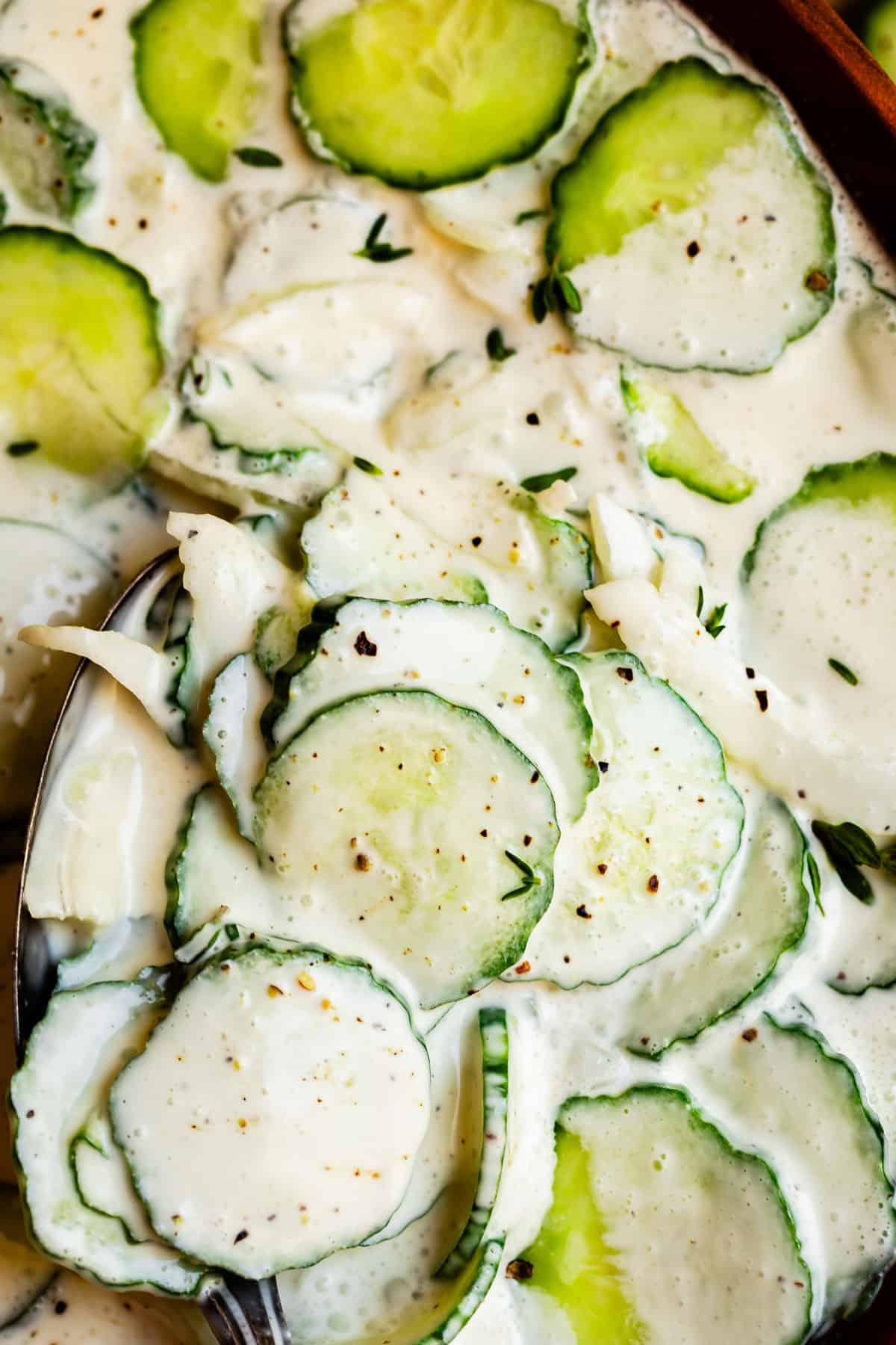 cucumber salad recipe shot from overhead with a creamy sauce and spoon in the corner.
