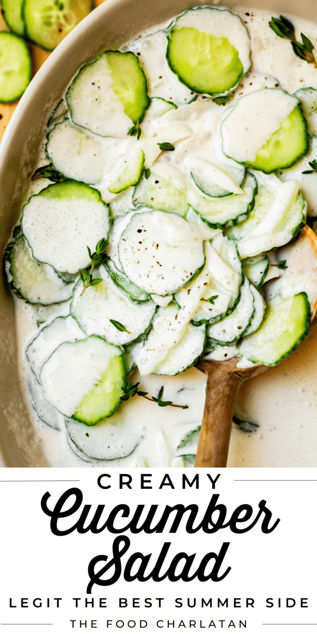 bowl of sliced cucumbers in a creamy dressing with wooden spoon.