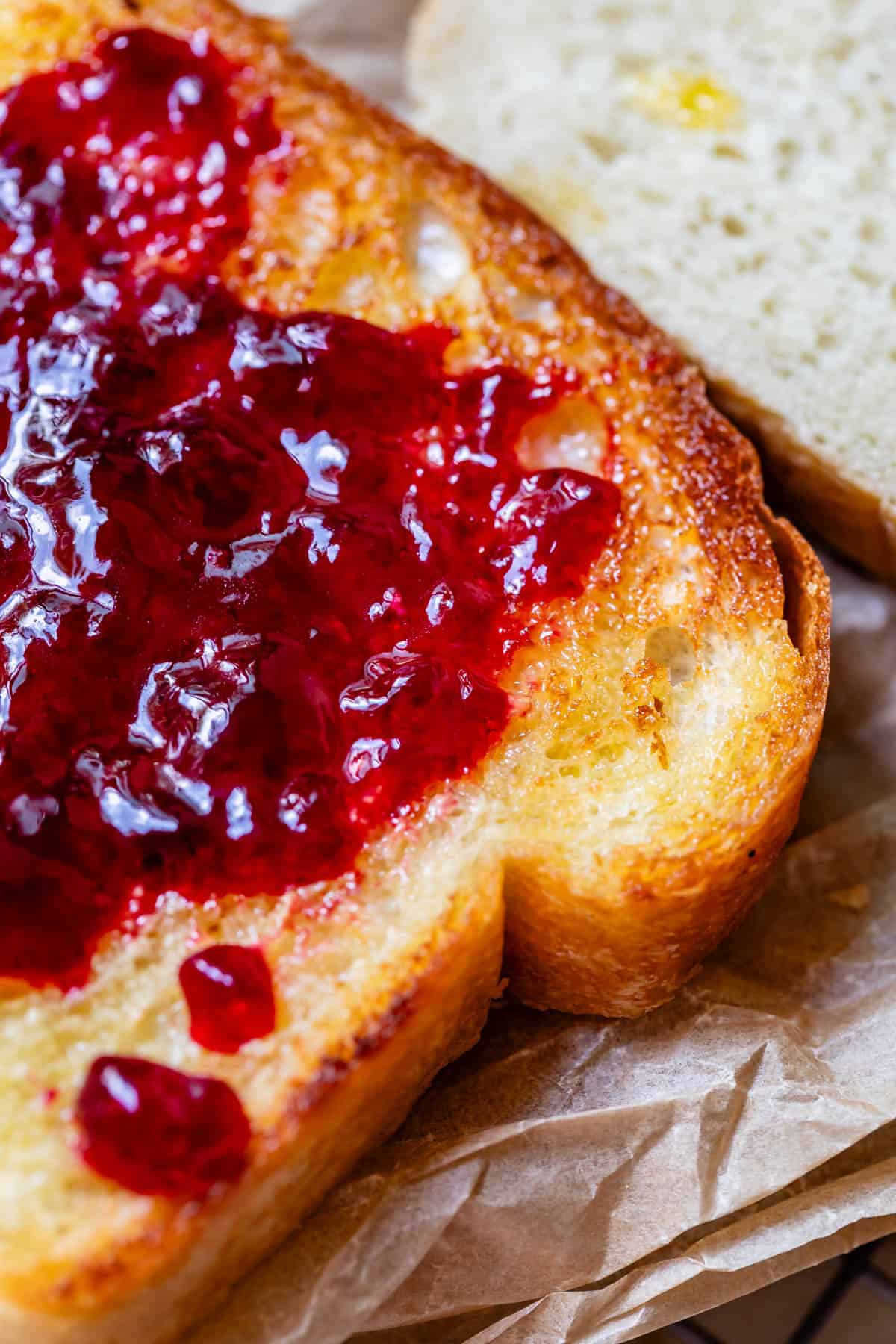 toasted and buttered white bread with jam, on parchment paper.
