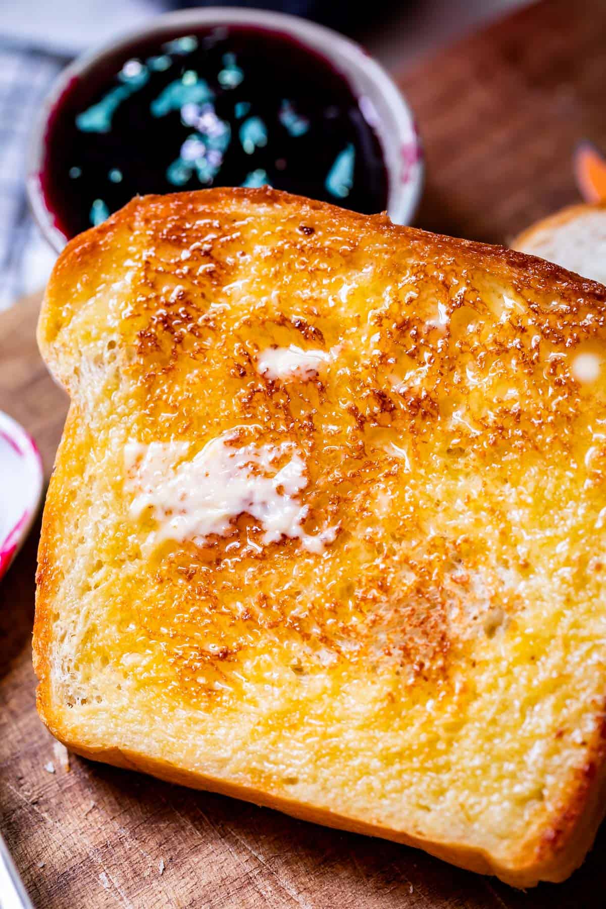 close up of a toasted slice of white bread with butter melting into all the nooks and crannies.