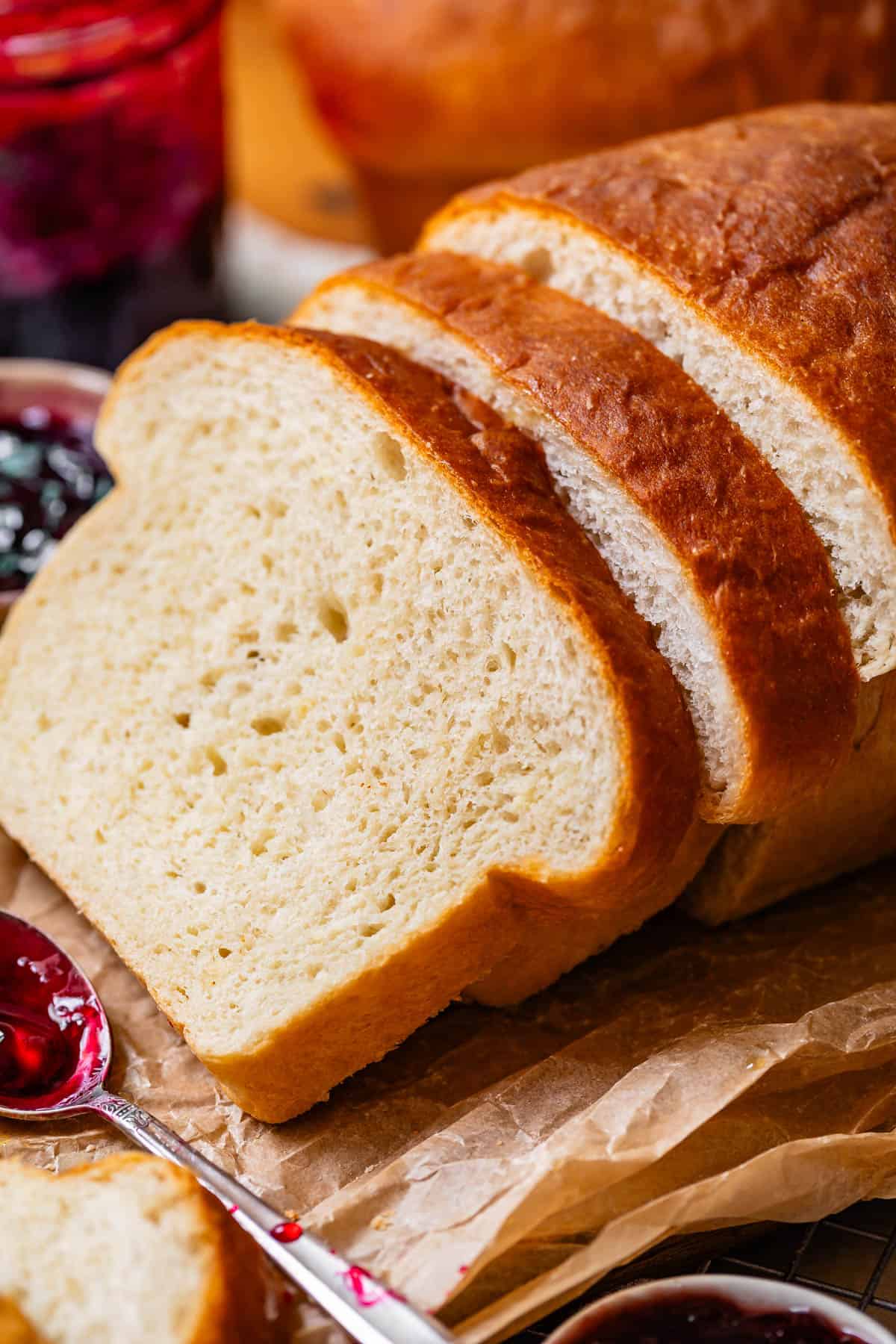 close up of three slices of bread on top of parchment paper with a spoon full of jam next to them.