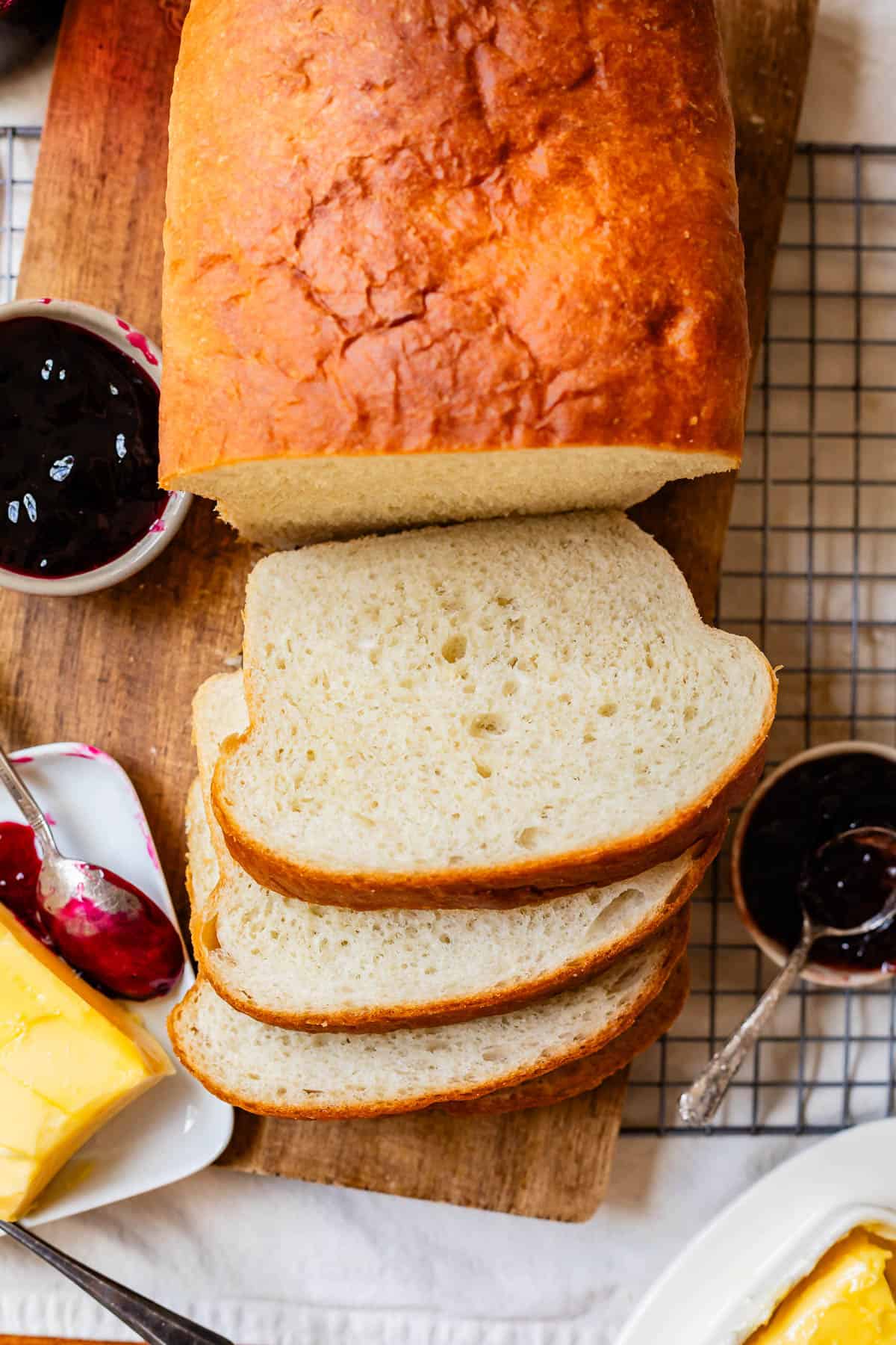 Looking down on a loaf of white bread with three cut slices on top of a wood cutting board.