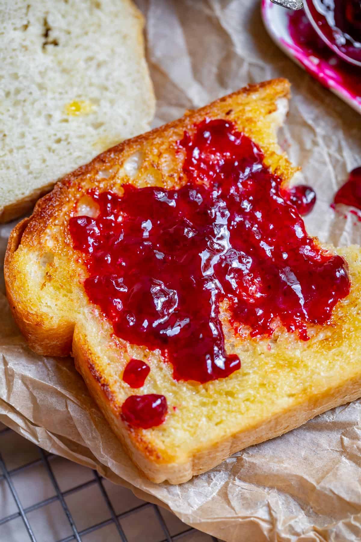 a slice of toasted and buttered white bread with a nice smear of jam across the top.