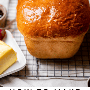 a whole loaf of uncut white bread out of the pan sitting on a cooling rack.