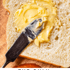 a butter knife spreading softened butter on a single piece of homemade white bread .