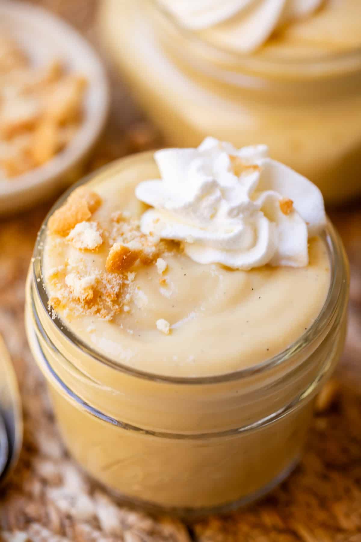 small mason jar filled to the brim with from scratch vanilla pudding, with whipped cream.