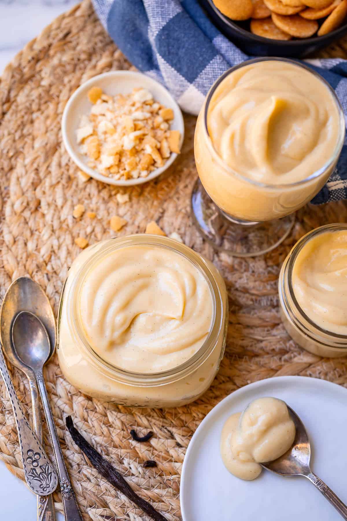 a cup, mason jar, and larger glass jar all filled with homemade vanilla pudding.