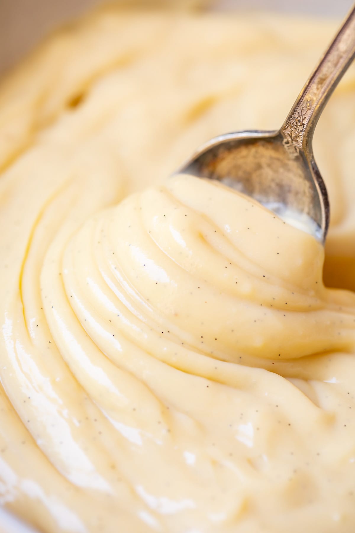 close up of creamy vanilla pudding from scratch being swirled but a spoon.