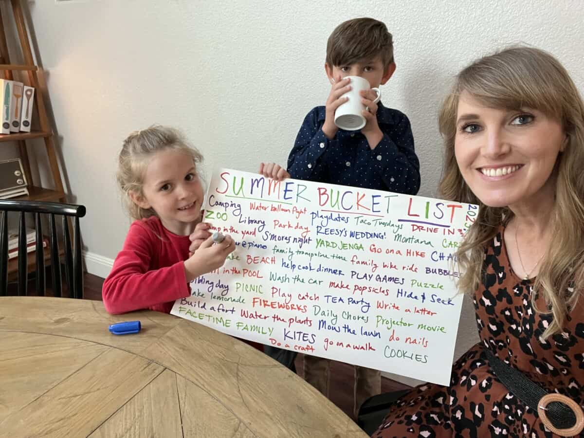 3 people holding up a poster with a summer bucket list on it.