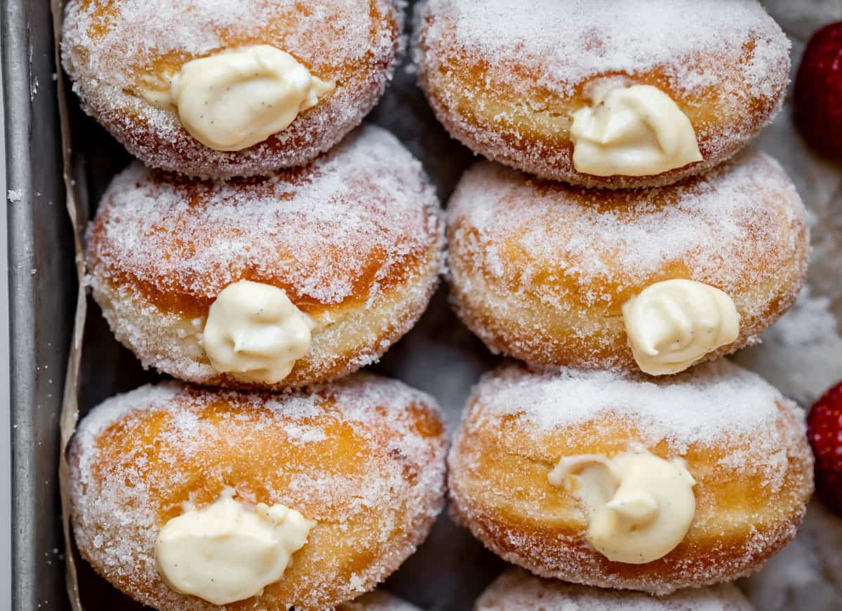 overhead shot looking down on the top of sugar rolled, cream filled donuts in a tray.